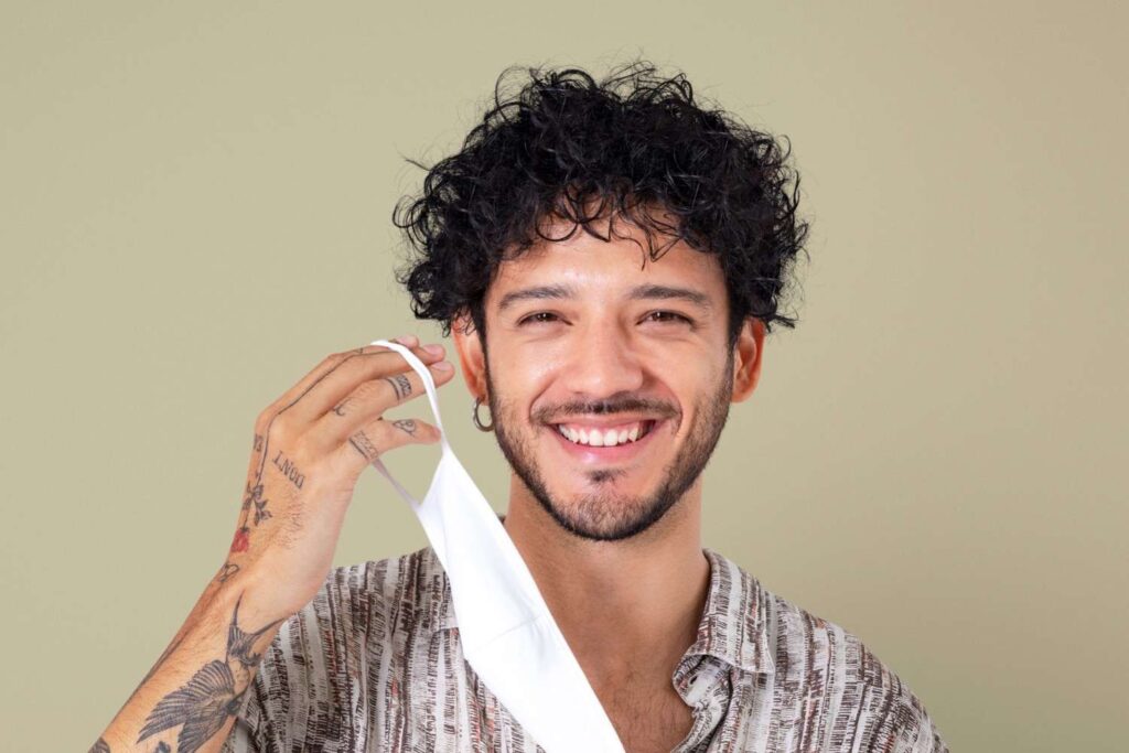 Man smiling while holding a face mask.